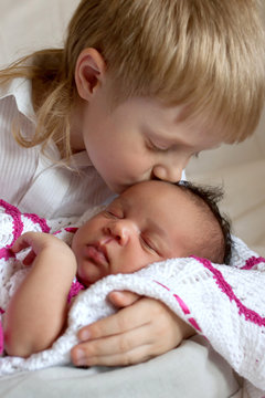 Multiracial family concept. Brother kissing newborn