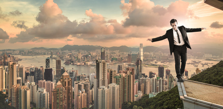 businessman in equilibrium on egde of the building