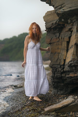Beautiful young woman goes along the coast.