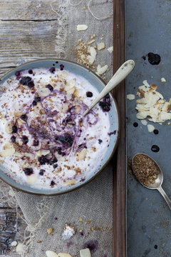 white yogurt with blackberries muesli and almond slices on bowl