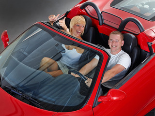 Young couple has fun to drive a red roadster