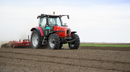 Naklejka premium Preparing land for sowing at spring, farmer in tractor