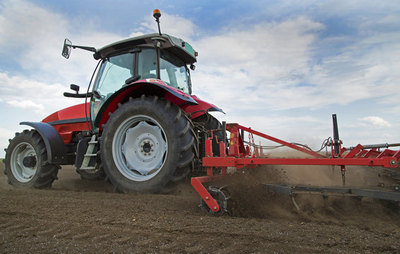Close-up of griculture red tractor cultivating field