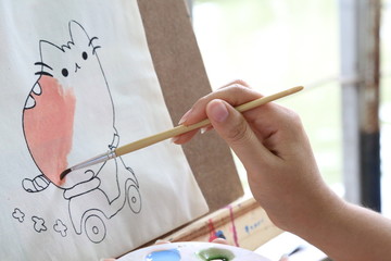 woman hand paints a cat picture with a brush