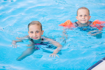Fototapeta na wymiar Two cute little girls in swimming pool