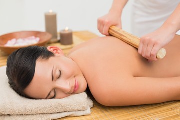 Obraz na płótnie Canvas Beautiful brunette enjoying a bamboo roller massage