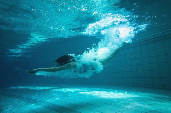 Athletic swimmer smiling at camera underwater