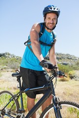 Fit cyclist riding in the countryside smiling at camera