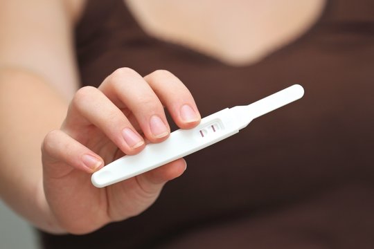 positiver Schwangerschaftstest gezeigt von junger Frau