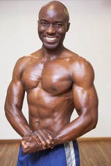 Fototapeta na wymiar Smiling shirtless muscular man posing in gym
