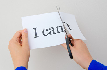 Female hand cutting paper with words. Concept.