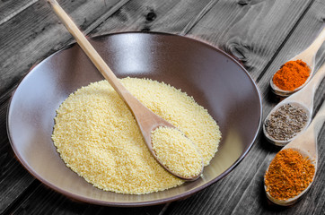 Spice on spoon with bowl of couscous
