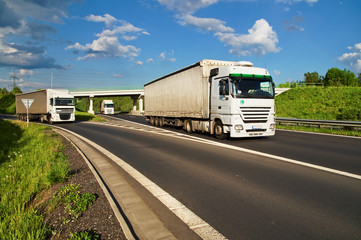 White trucks driving along the highway through the countryside