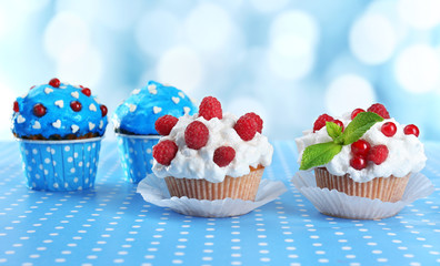 Tasty cupcakes on table, on bright background