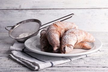 Tasty bagels with powdered sugar, on wooden background