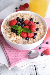 Tasty oatmeal with berries on table close-up