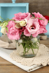 Bouquet of eustoma flowers in vase on wooden background