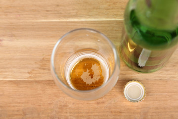 Bottle and glass with cold drink, on wooden background