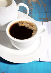 Cup of coffee, creamer on color wooden background