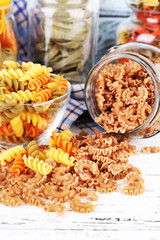 Colorful pasta in glass jars on wooden background