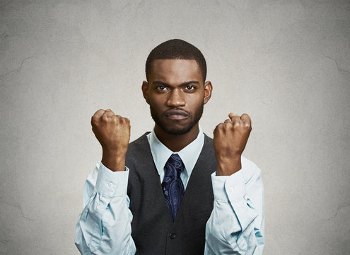 Angry man with fists up in air, isolated on grey background 