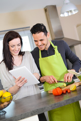 happy young couple preparing organic salad together in kitchen