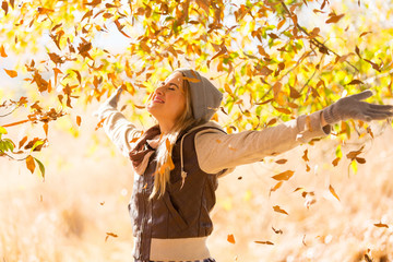 autumn leaves falling on happy young woman