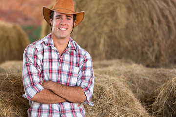 Naklejka na ściany i meble cowboy standing against hay bales