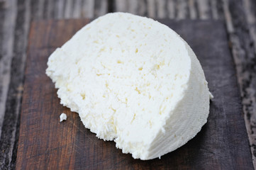 A piece of cheese on a wooden board