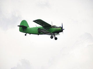 Fototapeta na wymiar small green airplane flying in overcast sky
