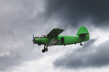 small green airplane flying in dark grey sky