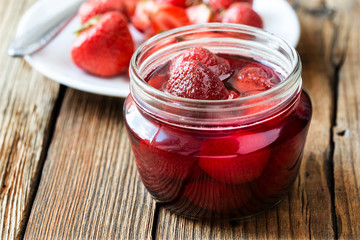 Strawberry jam in glass jar on wooden table