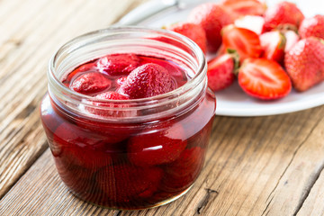 Strawberry jam in glass jar on wooden table