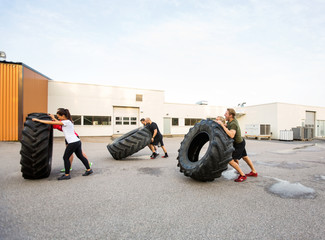 Athletes Doing Tire-Flip Exercise Outdoors © Tyler Olson