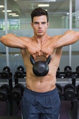 Fototapeta na wymiar Muscular man lifting kettle bell in gym
