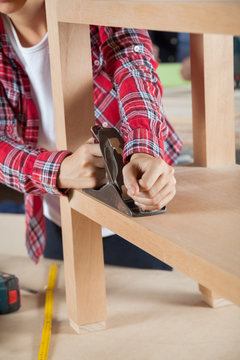 Carpenter Using Planer On Wooden Shelf