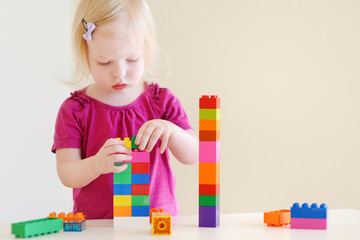 Cute toddler girl playing with colorful blocks
