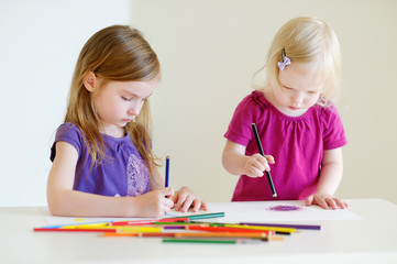 Two little sisters drawing with colorful pencils