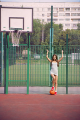 Beautiful young woman playing basketball outdoors
