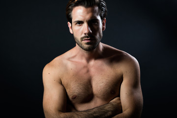 Fototapeta premium Handsome muscular male model posing over black background.