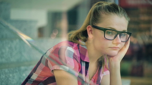 Sad, pensive teenage girl sitting on stairs in shopping mall