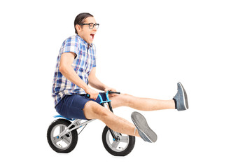 Fototapeta na wymiar Carefree young guy riding a small bike