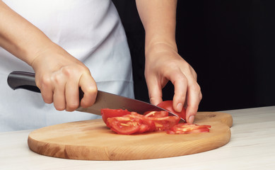 Female hands cutting tomato