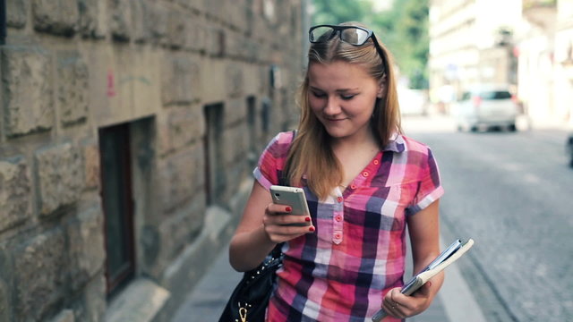 Young teenager walking with smartphone in the city