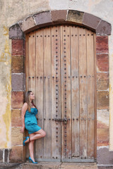 young woman in long dress standing in front an old door.  Focus