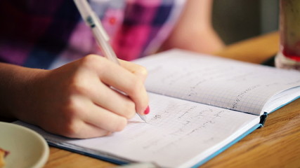 Teenage girl hands writing in notebook, doing homework