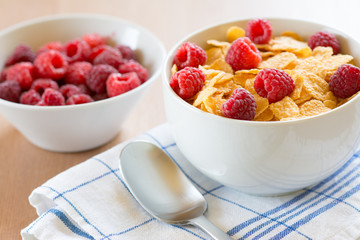Cornflakes and red rasberries in a white bowl