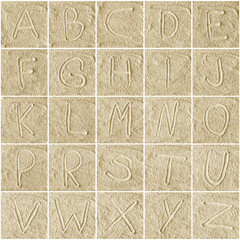 handwritten alphabet letters on sand