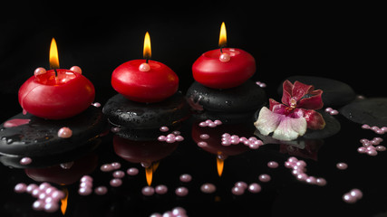 spa setting of red candles, orchid cambria flower on zen stones