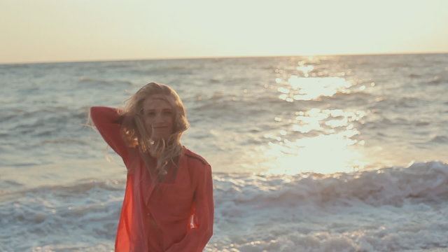 Young blond girl with long hair in red blouse on the beach